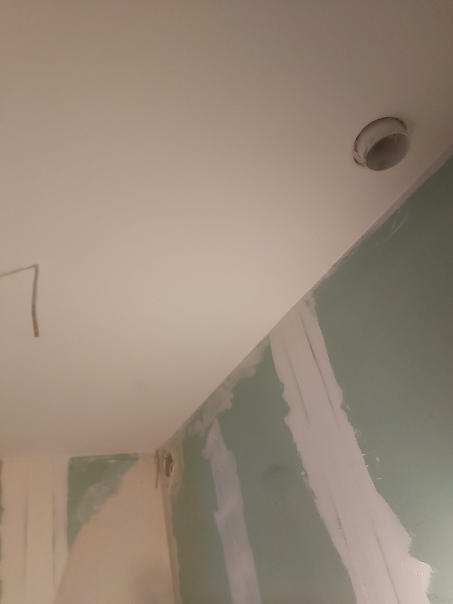 Sufit i narożnik ściany z płyt gipsowo-kartonowych, widoczny otwór pod oprawę oświetleniową oraz spoiny po szpachlowaniu