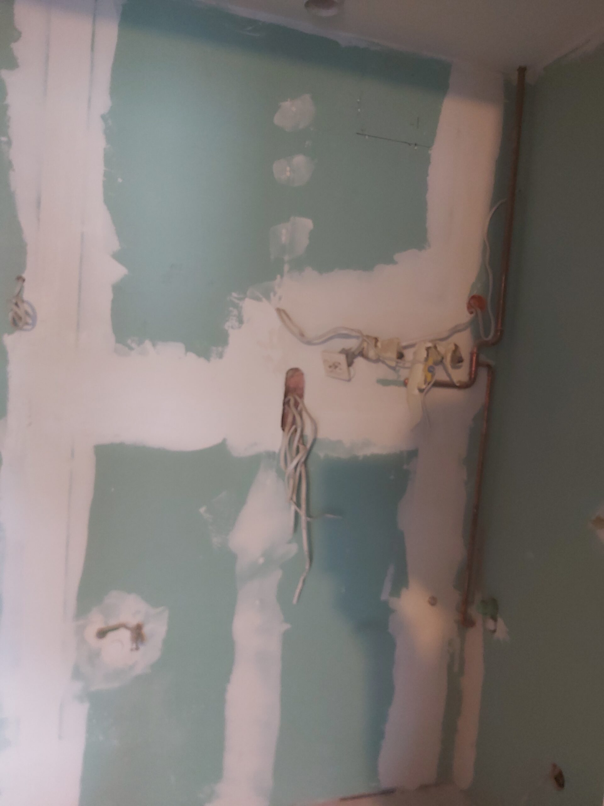 Ściana z płyt gipsowo-kartonowych w trakcie szpachlowania z widoczną instalacją elektryczną