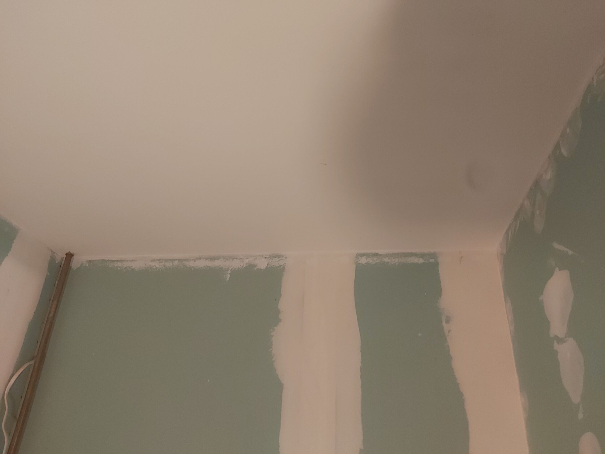 Połączenie sufitu ze ścianą z płyt gipsowo-kartonowych podczas szpachlowania spoin