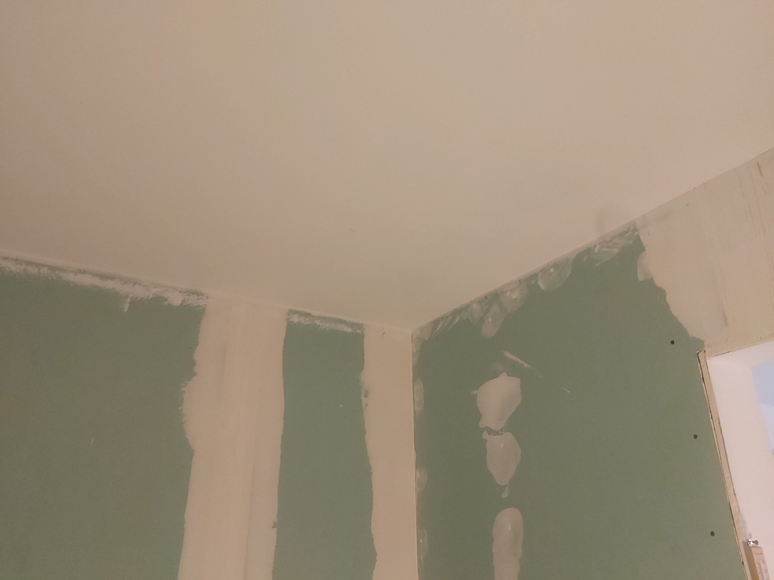 Narożnik sufitu i ścian z płyt gipsowo-kartonowych w trakcie szpachlowania spoin