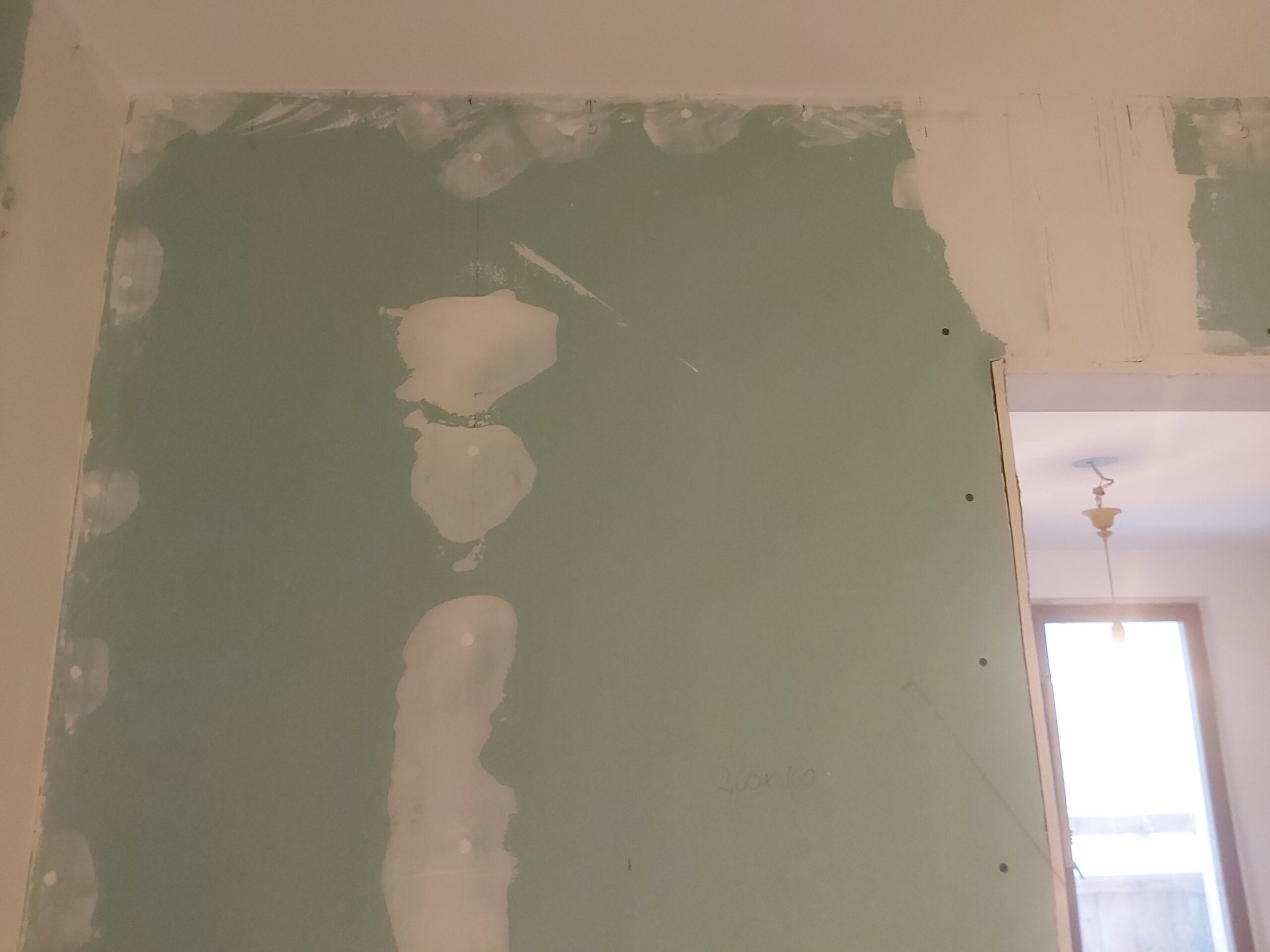 Szpachlowana ściana z płyt gipsowo-kartonowych przy otworze drzwiowym – etap prac wykończeniowych