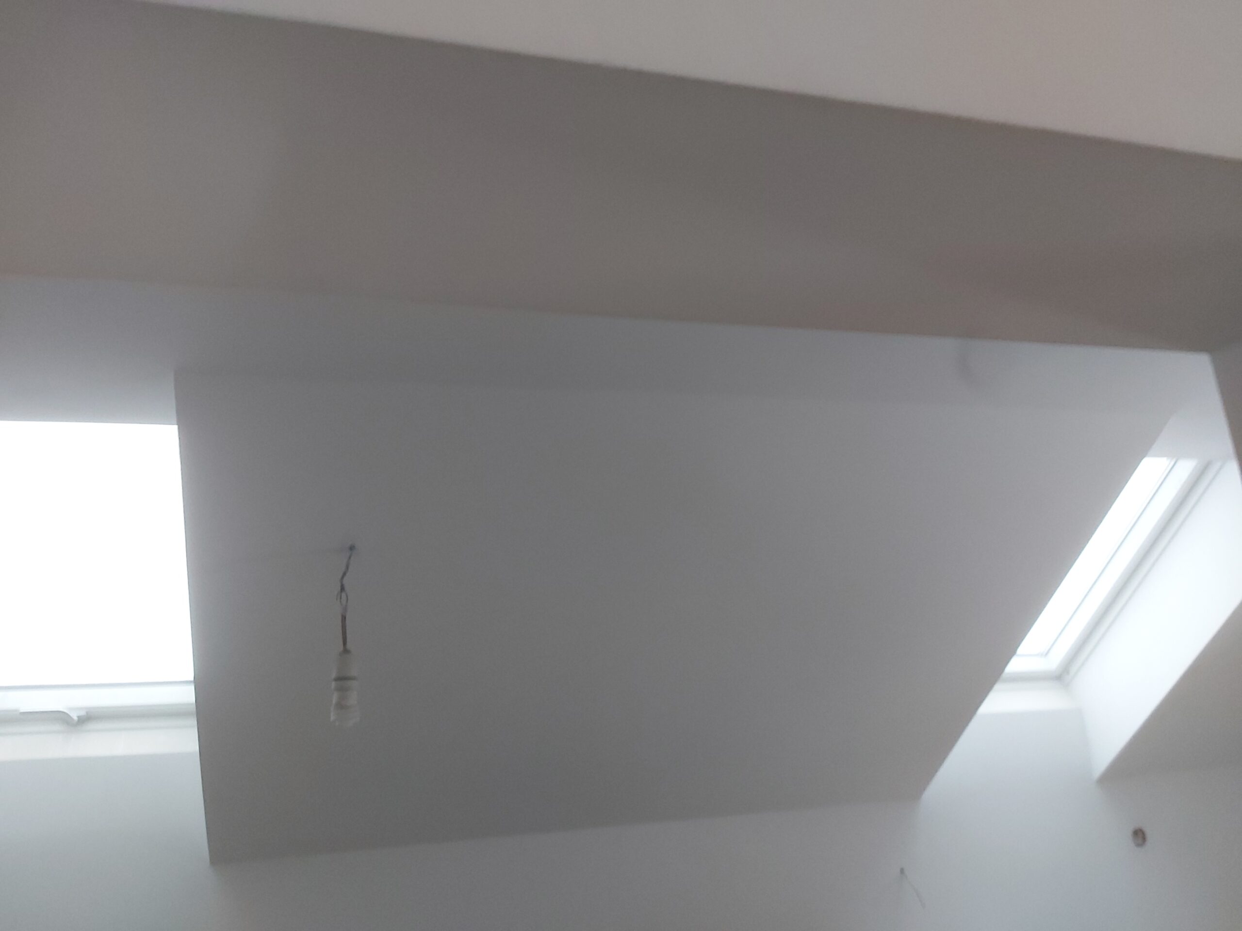 Biały sufit ze skosem i dwoma oknami dachowymi po zakończeniu prac remontowych