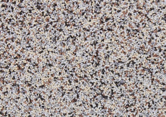 Zbliżenie dekoracyjnej powierzchni ściennej wykonanej z drobnego, wielokolorowego kruszywa mineralnego.