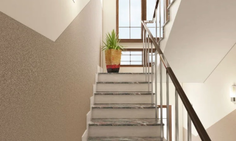 Nowoczesna klatka schodowa z kamiennymi stopniami, metalową balustradą i ścianą o dekoracyjnej fakturze.