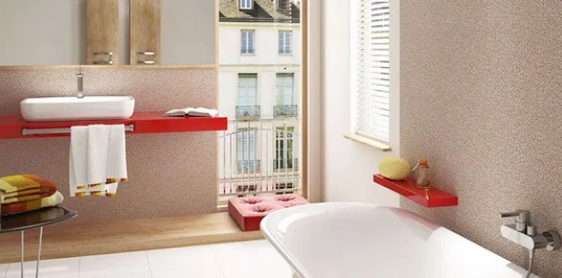 Jasna łazienka z wanną wolnostojącą, czerwonymi półkami i ścianą o dekoracyjnej fakturze.
