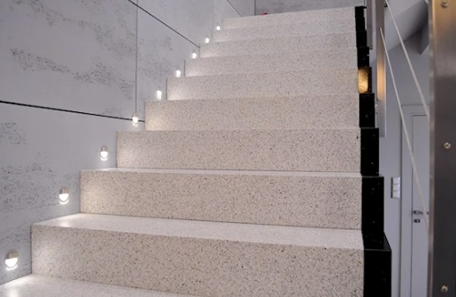 Nowoczesne schody wykończone dekoracyjną powierzchnią z kruszywa mineralnego z podświetleniem LED.