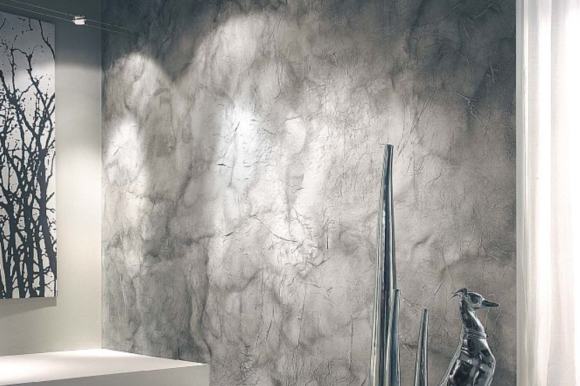 Dekoracyjna ściana w salonie z efektem stiuku weneckiego w odcieniach szarości, podświetlona punktowym oświetleniem.