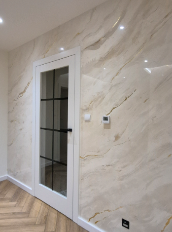 Ściana w przedpokoju wykończona stiukiem weneckim w kolorze jasnego marmuru z delikatnymi złotymi żyłami.